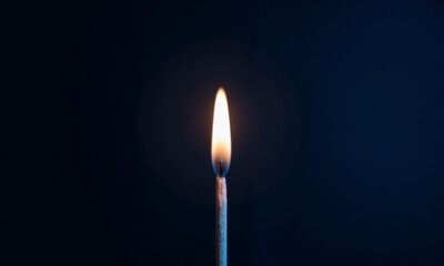 A Single Lit Match its Flame Bright Against a Dark Blue Background