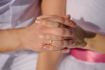 Man and woman, newlyweds holding hands with blurred background.