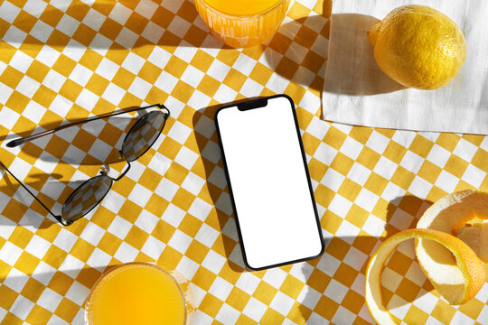 Smartphone with white screen on yellow and white checkered tablecloth.