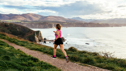 Woman running by coastline trail