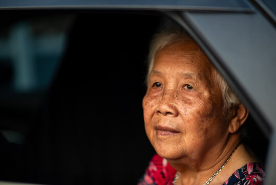 Elderly woman resting in car at sunset