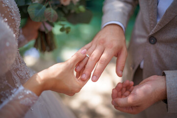 Newlyweds exchange rings, groom puts the ring on the bride's hand.