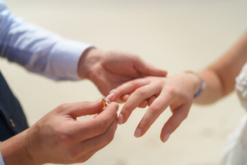 Newlyweds exchange rings, groom puts the ring on the bride's hand.