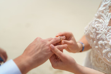 Newlyweds exchange rings, groom puts the ring on the bride's hand.