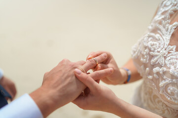 Newlyweds exchange rings, groom puts the ring on the bride's hand.