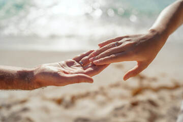 Man and woman, newlyweds holding hands with blurred background.