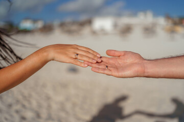 Man and woman, newlyweds holding hands with blurred background.