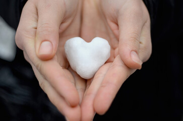 Snow in the shape of a heart in a woman's hands.