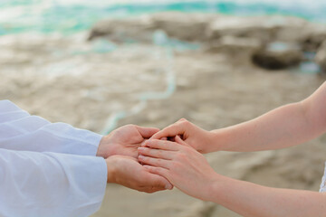 Man and woman, newlyweds holding hands with blurred background.