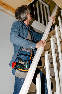 Man Installing Wooden Railing on Staircase During Home Renovation