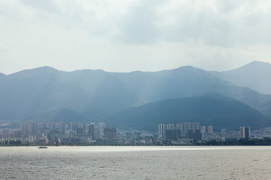 City skyline with mountains and lake under cloudy sky