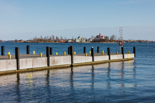 Wooden dock on calm water with island buildings in background