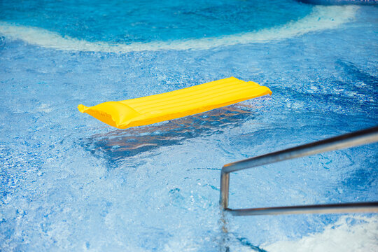 Yellow inflatable mattress floating in swimming pool