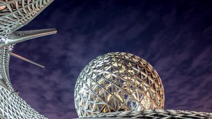 Futuristic metallic geodesic dome glowing under a cloudy night sky, creating a mesmerizing spectacle of modern architecture and innovative design - Powered by Adobe