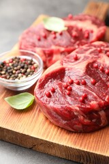 Pieces of raw beef meat and spices on gray table, closeup