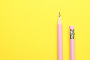 Two graphite pencils on yellow background, top view. Space for text