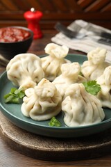 Delicious khinkali served with cilantro on wooden table, closeup