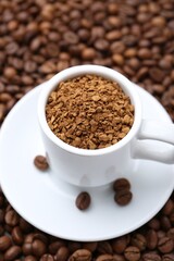 Cup with granulated instant coffee on beans, closeup
