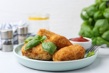 Tasty fried croquettes, basil and sauce on white tiled table, closeup