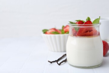 Tasty panna cotta with caramel, strawberries, mint and vanilla pods on white table, closeup. Space for text