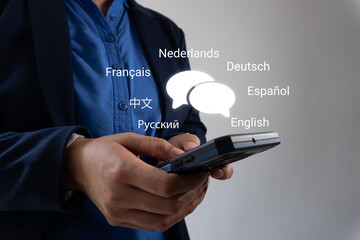 Businessman hands holding smartphone with two speech bubbles icon and various languages...
