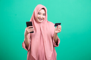 Modern muslim woman shopping online, holding card and smartphone