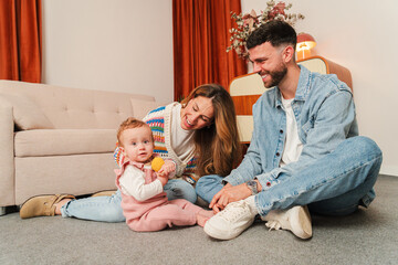 A heartwarming family moment featuring parents joyfully engaging with their adorable baby, creating...