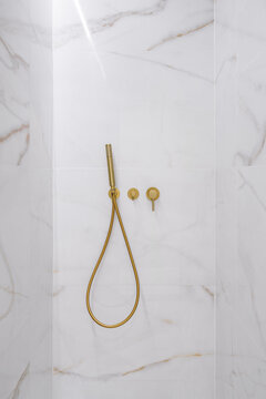Close-up of marble shower with gold fixtures