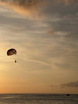 Parasailing over calm sea during golden sunset