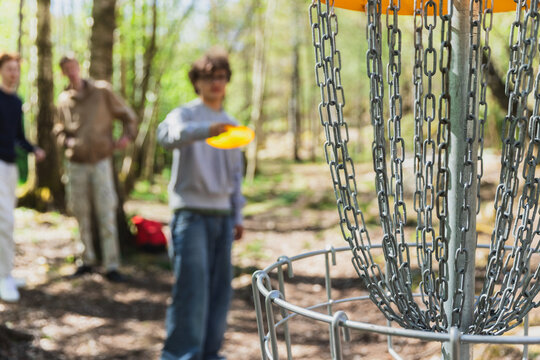 Person Playing Disc Golf, Aiming a Frisbee at the Basket