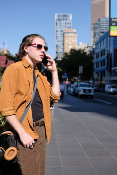 Person Talking on Phone on Melbourne Sidewalk with Urban Backdrop