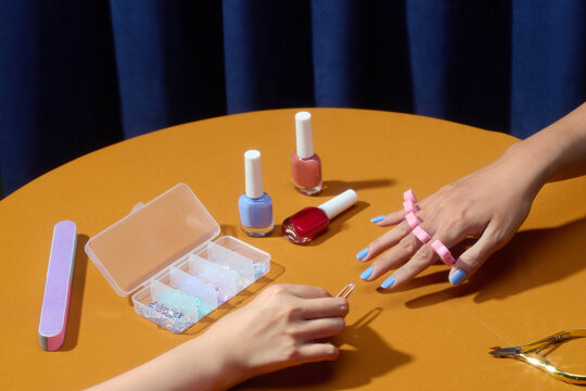 A person's hands are featured while using nail polish