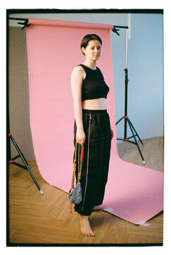 Model poses against a pink backdrop during a fashion shoot