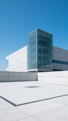 Fototapeta premium Modern building with glass facade and concrete walls under a clear blue sky