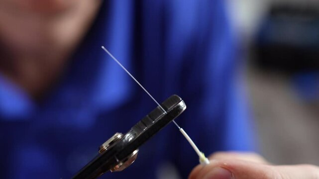A fiber technician strips and cleaves an optical fiber cable using a precision stripping tool
