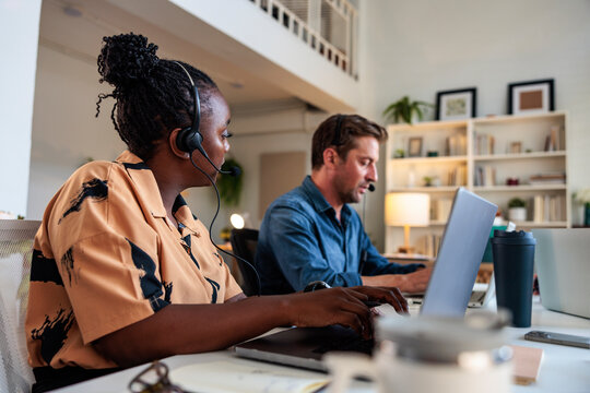 Two people working from home with headsets and laptops.