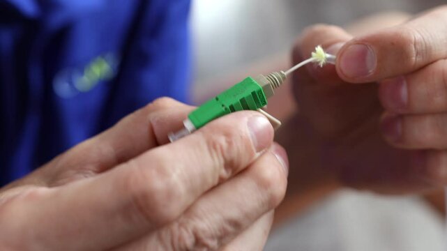 Cleaned and stripped fiber optic cable being inserted and secured into an APC (angled physical contact) connector with a click-lock closure 