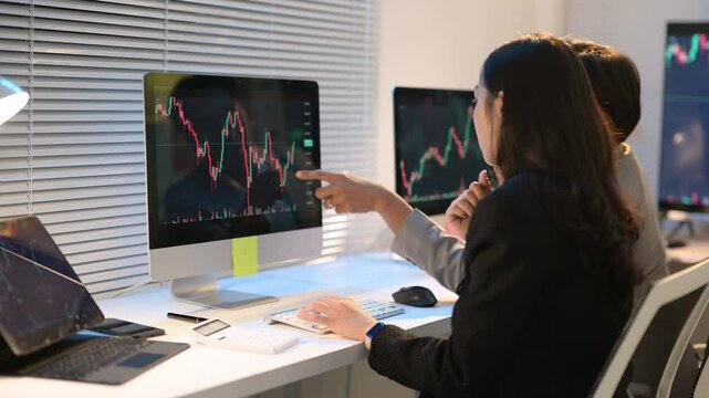 Businesswomen analyzing financial charts on computer screen