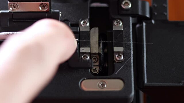 Close up shot of fiber core being inserted and precisely cleaved inside a fiber cleaver