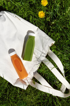 Orange and green smoothie bottles on reusable shopping bag.  