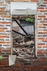 Window frame of a collapsed house without shutters, revealing scattered bricks and wood debris...