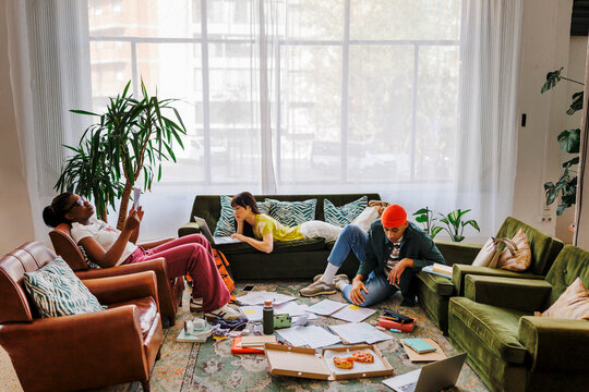 Group of students studying and eating pizza in messy living room
