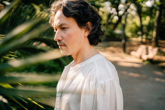 Side profile portrait in white shirt near garden path