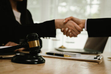 Two professionals are signing a legal agreement at a desk, with a judge’s gavel nearby. The scene reflects law, business contracts, and formal documentation.x