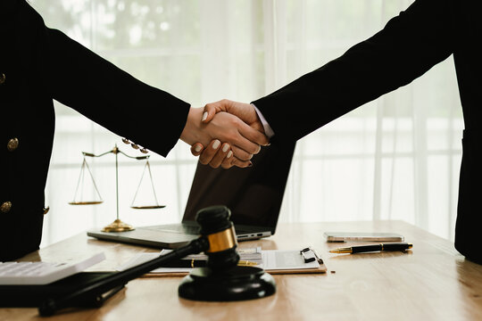 Two professionals are signing a legal agreement at a desk, with a judge&rsquo;s gavel nearby. The scene reflects law, business contracts, and formal documentation.x