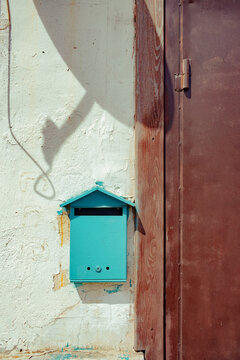 Colorful mailbox and shadow on a rustic wall