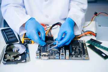The technician is putting the CPU on the socket of the computer motherboard. electronic engineering...
