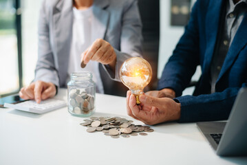 Showcasing innovation and finance. Business professionals with a glowing light bulb, coins,