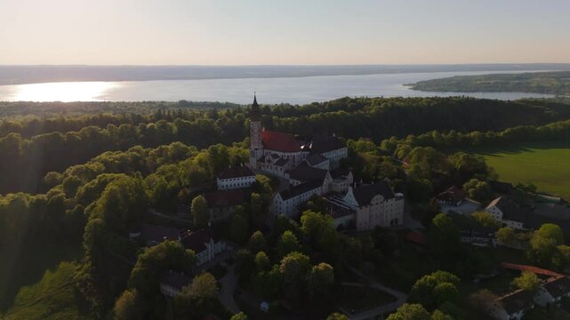 Drone footage of Kloster Andechs on Holy Mountain in Upper Bavaria, Germany. View of monastery, baroque church, lake Ammersee and green countryside near Munich at golden hour. Luftbild Heilige Berg. 