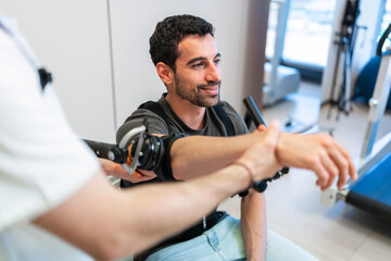 Doctor assisting patient using robotic physiotherapy equipment